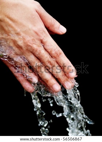 Young woman cleaning her hand with pure water on black background