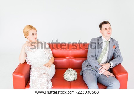 Beautiful young happy smiling pregnant couple sitting on sofa, isolated on white background