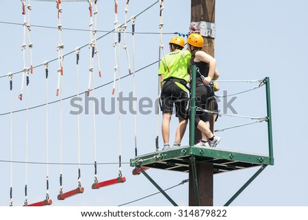 BOLOGNA,ITALY-MAY 31,2015:people hanging on a equipped path walks among cordage, ropes and obstacles during a sunny day.