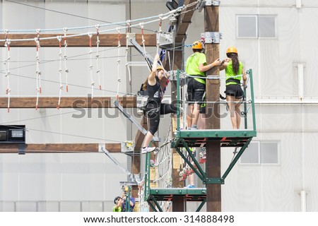 BOLOGNA,ITALY-MAY 31,2015:Group of people hanging on a equipped path walks among cordage, ropes and obstacles during a sunny day.