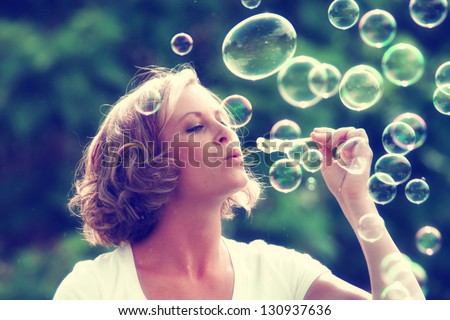 a beautiful woman blowing bubbles toned with a retro vintage instagram filter