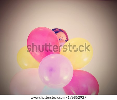 a pretty girl hiding behind a bunch of balloons done with a retro vintage instagram filter (focus on the balloons)