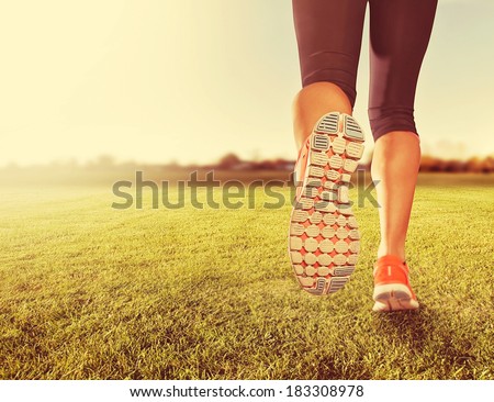 an athletic pair of legs on grass during sunrise or sunset - done with a soft vintage instagram  like filter