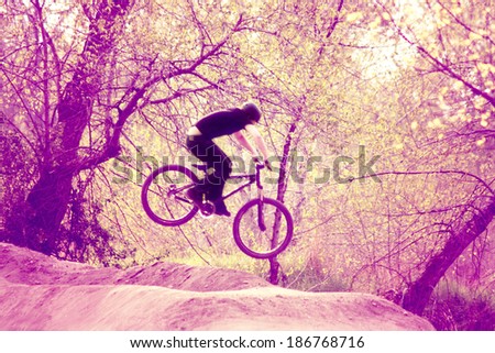 a biker riding a bicycle over a jump done with a retro vintage instagram like filter