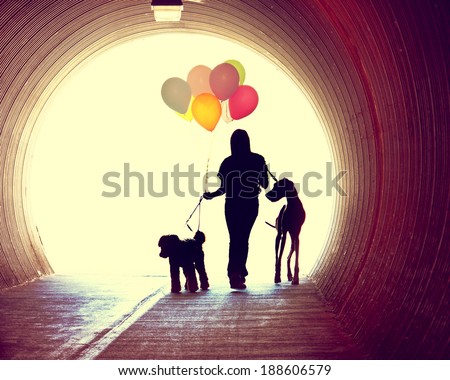 a girl at the end of a tunnel holding balloons and two dogs done with an instagram vintage retro filter