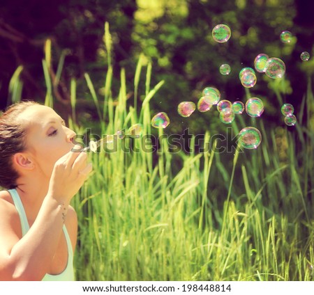 a pretty girl blowing bubbles  done with an instagram like filter