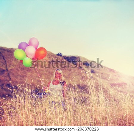 a pretty woman enjoying summer outside with a bunch of balloons toned with a retro vintage instagram filter