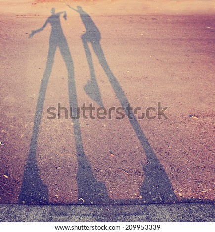 shadow of two people play fighting in the street toned with a retro vintage instagram filter