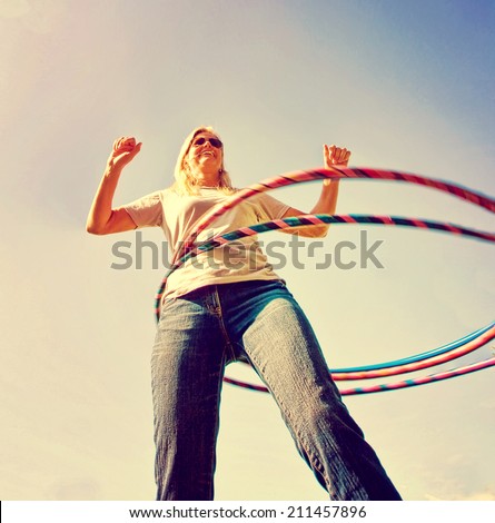a woman hula hooping on a clear day toned with a retro vintage instagram filter
