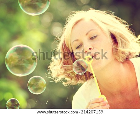 a pretty girl blowing bubbles toned with a retro vintage instagram filter effect