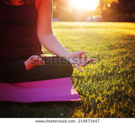 hands of a woman meditating in a yoga pose on the grass toned with warm filter effect
