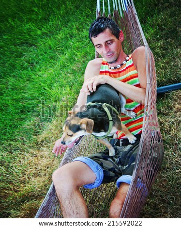 a young man in a hammock cuddling with his chihuahua beagle mix dog