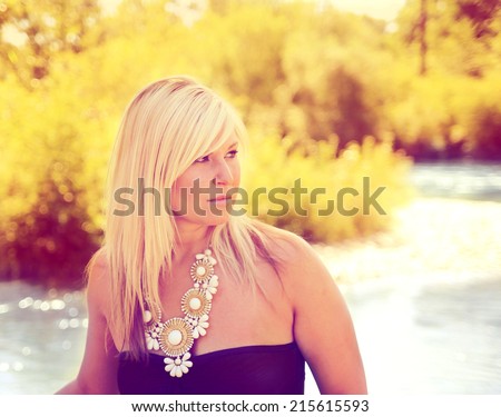 a pretty girl looking to the side by a sparkling river