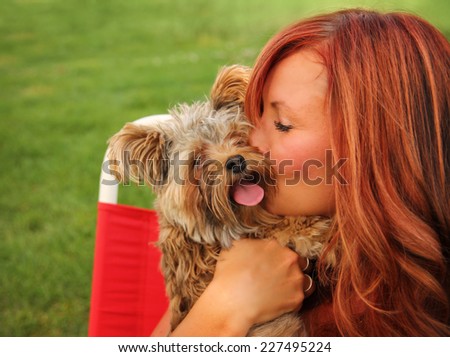 a woman with her beautiful dog cuddling outside at a park