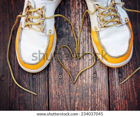 a pair of deck shoes on a nice wooden porch with the laces in a heart shape