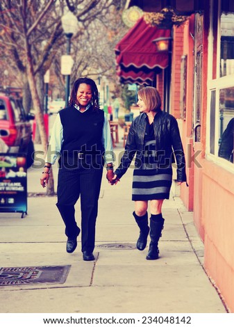 couple in love walking down a city street holding hands in a loving gesture toned with a retro vintage instagram filter effect