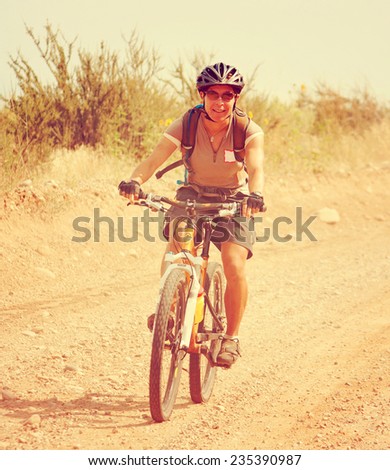 a girl riding a mountain bike in the hills toned with a retro vintage instagram filter effect