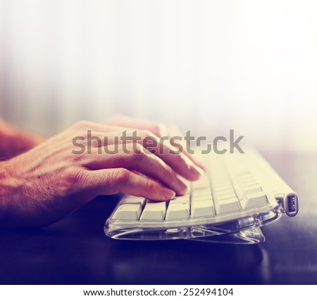 hands typing on laptop keyboard toned with a retro vintage instagram filter