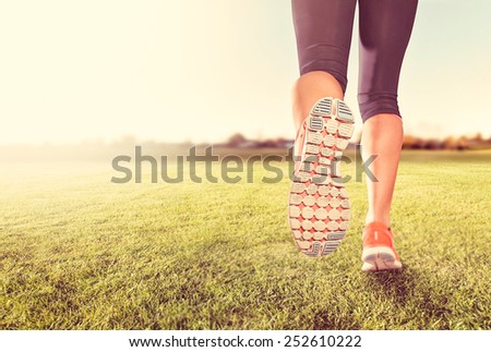 an athletic pair of legs on grass during sunrise or sunset - he