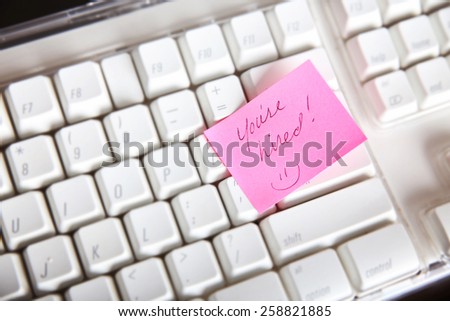 pink sticky note on an white keyboard with the text you\'re hired and a smiley emoticon face