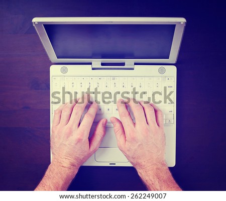 hands typing on a laptop keyboard toned with a retro vintage instagram filter