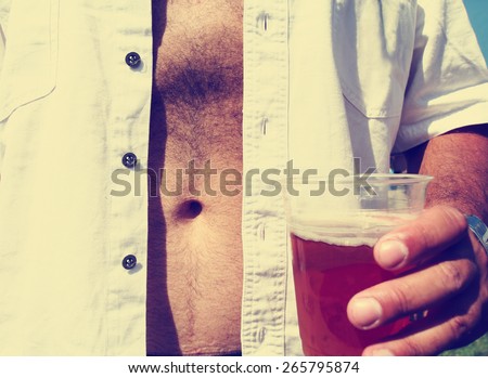 a man holding a beer in a cup with a bare belly toned with a retro vintage instagram filter effect app or action