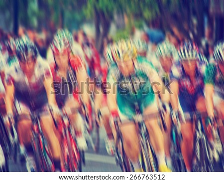 blurred image of a pack of bicycle riders rounding a corner toned with a retro vintage instagram filter effect app or action
