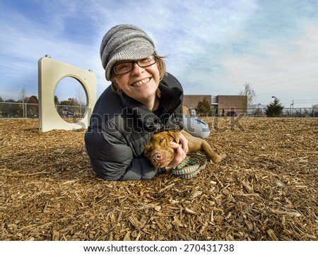 a woman wrestling with her dog at a local park during autumn