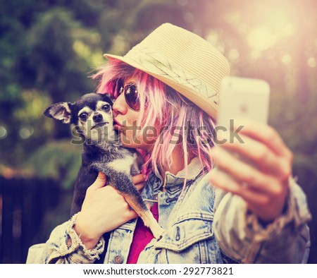 Young woman taking a selfie with a cute chihuahua dog toned with a retro vintage instagram filter effect app or action