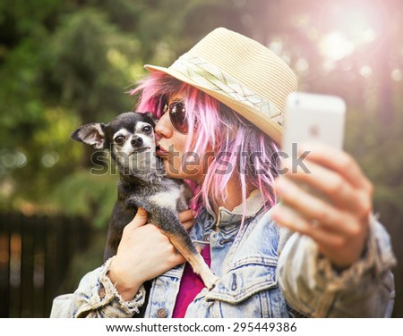 Young woman taking a selfie with a cute chihuahua dog toned with a retro vintage instagram filter effect app or action
