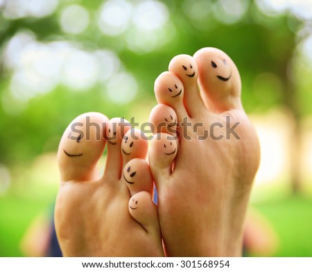 smiley faces on a pair of feet on all ten toes in a park setting