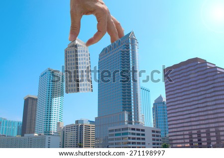 Urban development concept showing a hand moving a building into place in a beautiful cityscape.