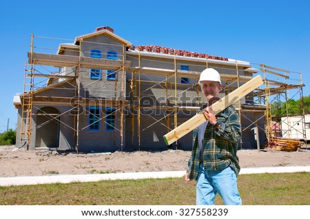 A construction worker contractor in a hard hat is walking through the front of a new house that is under construction