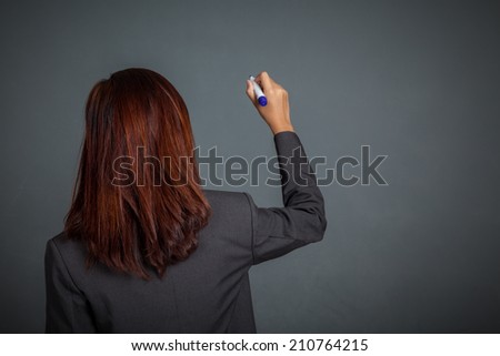 Back of Asian business girl write in the air on gray background