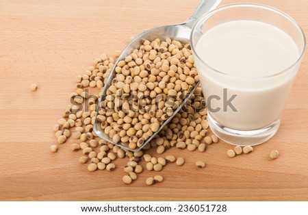 Soy milk in glass with soybeans and  transfer scoop on wood table