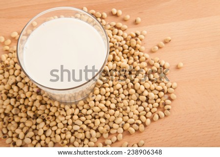 Soy milk in glass with soybeans on wood table