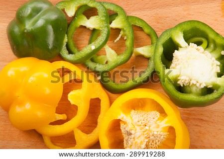 Cut yellow and green bell peppers on wooden cutting board