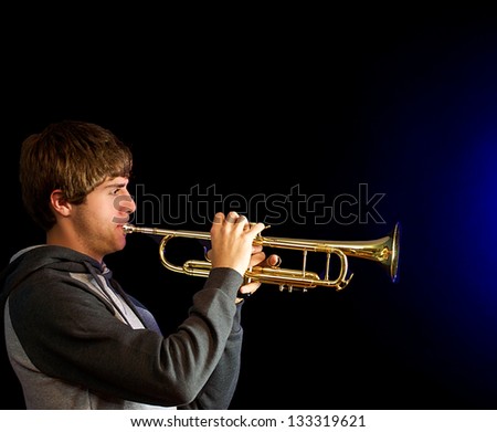 Young man playing a trumpet with a blue sound.