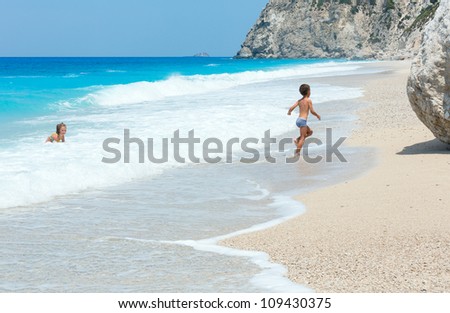 Two children have the water-based recreation on white beach near azure Ionian sea (Egremni, Lefkada, Greece)