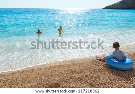 Family (mother with two children) have the water-based recreation on white Egremni beach (Ionian sea, Lefkada, Greece) and sunshine pass in water