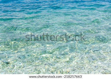 Sea surface with transparent water and stones on bottom. Nature background.