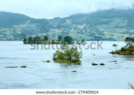 Summer cloudy fjord landscape with village on shore (Norway).