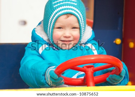 Little boy is learning to drive on the pleasure-ground.