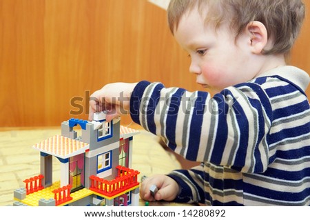 Small boy play with building set for children (built a house)