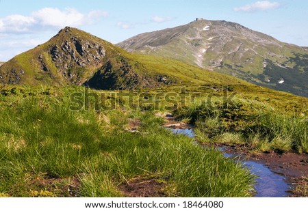 Summer mountain view with small puddle on path (with observatory ruins on Chornogora Ridge, Ukraine)
