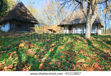 Ukrainian historical country wooden hut with thatched roof and autumn garden grass near