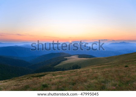Autumn sunrise mountain view with haze, forest and sun on sky (Carpathian, Ukraine)
