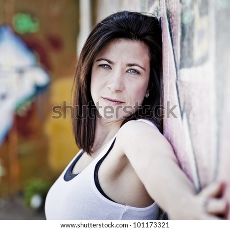 beautiful woman leaning against a graffiti covered wall