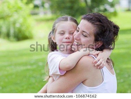 Pretty mother and daughter outside hugging portrait