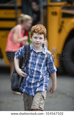 Young boy walking away from a school bus